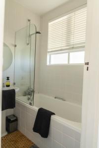 a white bathroom with a tub and a window at Studio Blue in Mouille Point in Cape Town