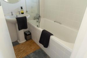 Studio Blue in Mouille Point في كيب تاون: حمام مع حوض أبيض ومغسلة وحوض استحمام
