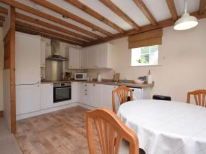 a kitchen with white cabinets and a table with chairs at 2 Bed in Ashford in the Water PK502 in Great Longstone