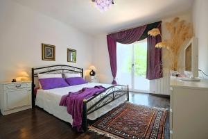 a bedroom with a bed with purple pillows and a window at Villa Rupena in Buzet