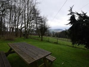 a wooden picnic table in a field with a fence at 3 Bed in Hope PK432 in Aston