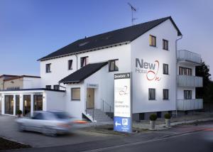 a car is driving past a white building at Hotel New In Guesthouse in Ingolstadt