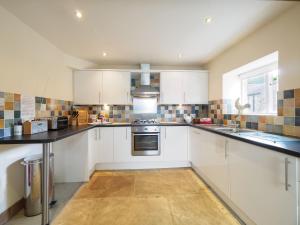 a kitchen with white cabinets and black counter tops at 3 Bed in Eyam PK833 in Eyam