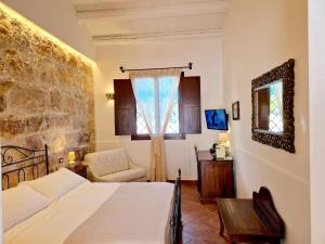 a bedroom with a bed and a chair and a window at Hotel La Corte Del Sole in Noto