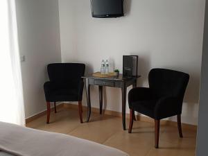 バターリャにあるCasa Ceedina Bed And Breakfast & Beautyの椅子2脚、テーブル、テレビが備わる客室です。