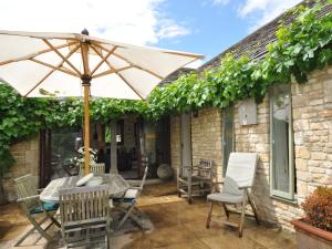 a patio with a table and an umbrella at 1 Bed in Stow-on-the-Wold 44932 in Naunton