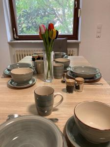 einen Tisch mit Teller, Tassen und Blumen in einer Vase in der Unterkunft Ferienwohnung Brenderweg in Koblenz