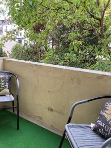 einen Balkon mit 2 Stühlen und einer Wand mit grünem Gras in der Unterkunft Ferienwohnung Brenderweg in Koblenz
