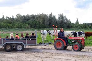 a man on a tractor pulling a trailer full of children at Boerderijcamping de Hinde in Dronten