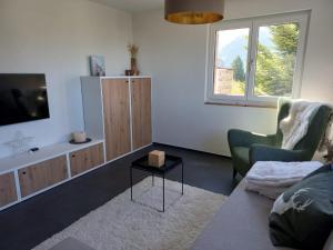 a living room with a tv and a chair and a table at Chalet Bergdohle in Rosswald