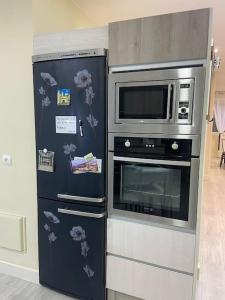 a refrigerator next to a stove and a microwave at La casa de las Flores in Ponferrada