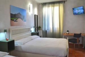 a bedroom with two beds and a table and a desk at DOMUS Hotel in Caselle Torinese