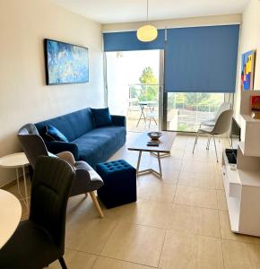 ein Wohnzimmer mit einem blauen Sofa und Stühlen in der Unterkunft PALLINIO COURT 402 Fig Tree Bay- Protaras Beach, IASONOS STR 7A in Protaras