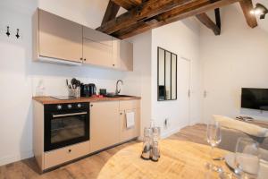 Una cocina con horno y una mesa con copas de vino. en Le Laurencin Sens - L Authentique - Cœur de ville, en Sens