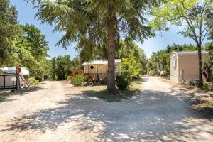een onverharde weg met een boom en een gebouw bij Camping la buissière in Barjac