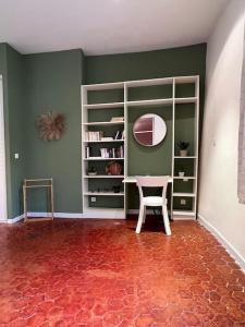 Habitación con paredes verdes, silla y espejo. en Appartement spacieux et calme à Aix en Provence en Aix-en-Provence