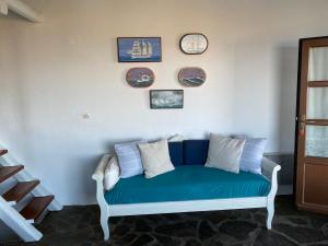 a blue couch against a white wall with clocks at Kea Amazing View Maisonette in Ioulida