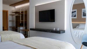 Una habitación de hotel con dos camas y un televisor en la pared. en La Hospedería - El Provencio, en El Provencio