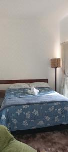 Una cama con un edredón azul con un teléfono. en Quartos para Hospedagem da Casa Amarela, en Campos do Jordão