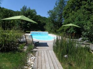 une piscine avec deux parasols verts et une terrasse en bois dans l'établissement Maison de vacances 9 personnes avec piscine, à Saint-Amand-de-Coly