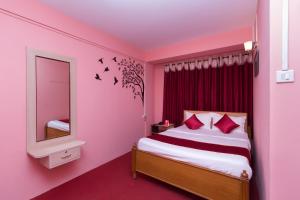 een roze slaapkamer met een bed en een spiegel bij OYO Flagship Balaji Guest House in Shillong