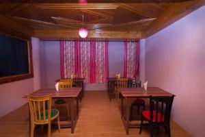 een restaurant met houten tafels en stoelen en paarse muren bij OYO Flagship Balaji Guest House in Shillong