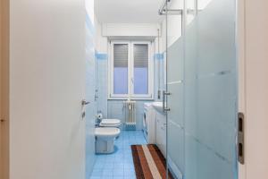 La salle de bains bleue est pourvue de toilettes et d'une fenêtre. dans l'établissement [AFFORI CENTRO METRO] Appartamento con camera e cucina, à Milan