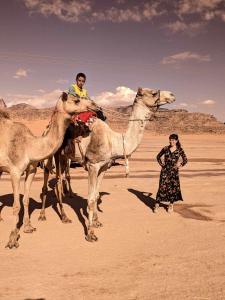 un hombre montando un camello con una mujer en el desierto en Shahrazad desert, Wadi Rum en Wadi Rum