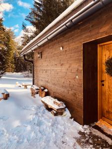 ein Blockhaus mit Schnee auf dem Boden daneben. in der Unterkunft Hájenka Libín in Prachatice