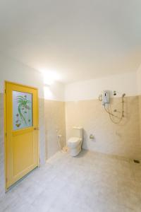 a bathroom with a toilet and a yellow door at Dias Legacy Bungalow in Talpe