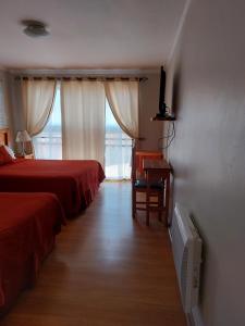 una camera da letto con due letti, una scrivania e una finestra di Hotel Solaris a Huasco Altre 37 foto