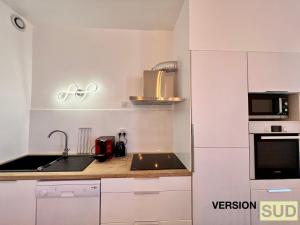 cocina blanca con fregadero y microondas en Version Sud- Appartement moderne proche gare, en Toulon