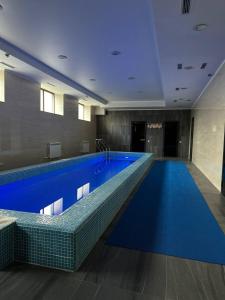 een groot zwembad in een gebouw met blauw water bij Sun Rise inn in Karagandy
