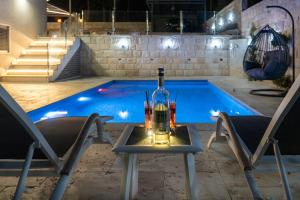 a bottle of wine and two chairs next to a swimming pool at אחוזת רעות in ‘En Ha‘Emeq