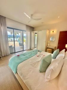 a large bed in a bedroom with a view of the ocean at Pineapple Beach Villas in Baie Lazare Mahé +55 photos