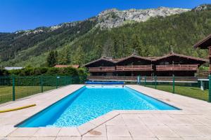 a swimming pool in front of a house with a mountain at Résidence Améthystes A2 ski in ski out - Happy Rentals in Chamonix