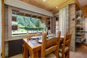 une salle à manger avec une table et une grande fenêtre dans l'établissement Résidence Améthystes A2 ski in ski out - Happy Rentals, à Chamonix-Mont-Blanc