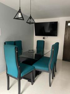 une table à manger avec des chaises bleues et une télévision dans l'établissement Hermoso y amplio apartamento en Niquia, à Bello