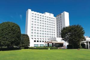 ein großes weißes Gebäude mit einem Rasen davor in der Unterkunft International Resort Hotel Yurakujo in Narita