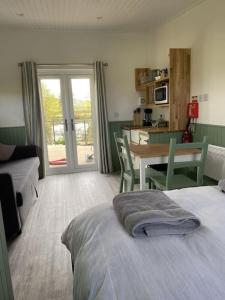 a bedroom with a bed and a table and a kitchen at The Lily Pod in New Abbey