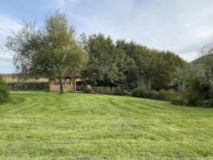 a large grass field with a house and trees at The Lily Pod in New Abbey