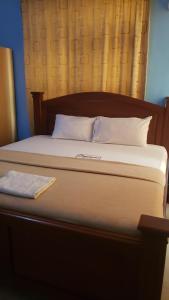 a bed with a wooden headboard and white pillows at Dreamers Lodge in Prampram