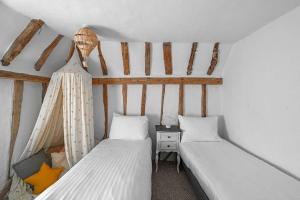 a bedroom with two beds and a nightstand with at Micawber Cottage, Rattlesden in Rattlesden