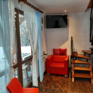 uma sala de estar com uma cadeira vermelha e uma televisão em 3 kroki od sosny Domek w lasku Sitaniec em Zamość