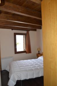 1 dormitorio con cama blanca y ventana en Hostal La Muntanya, en Castellar de NʼHug