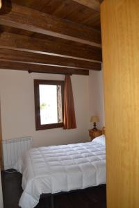 a bedroom with a white bed and a window at Hostal La Muntanya in Castellar de NʼHug