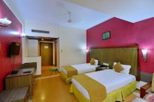 een hotelkamer met 2 bedden en een rode muur bij Hotel Clarks Grand , Gorakhpur in Gorakhpur