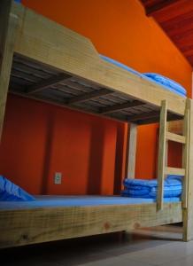 2 Etagenbetten in einem Zimmer mit orangefarbener Wand in der Unterkunft Geckos Hostel in Florianópolis