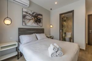 a bedroom with a white bed with towels on it at Studio 41 at the vibrant Olo living guesthouse in Paceville