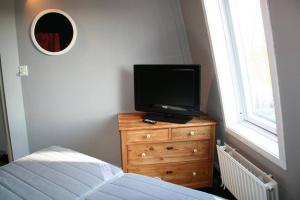 a bedroom with a television on a dresser with a bed at Liguster 56* in Nieuwvliet